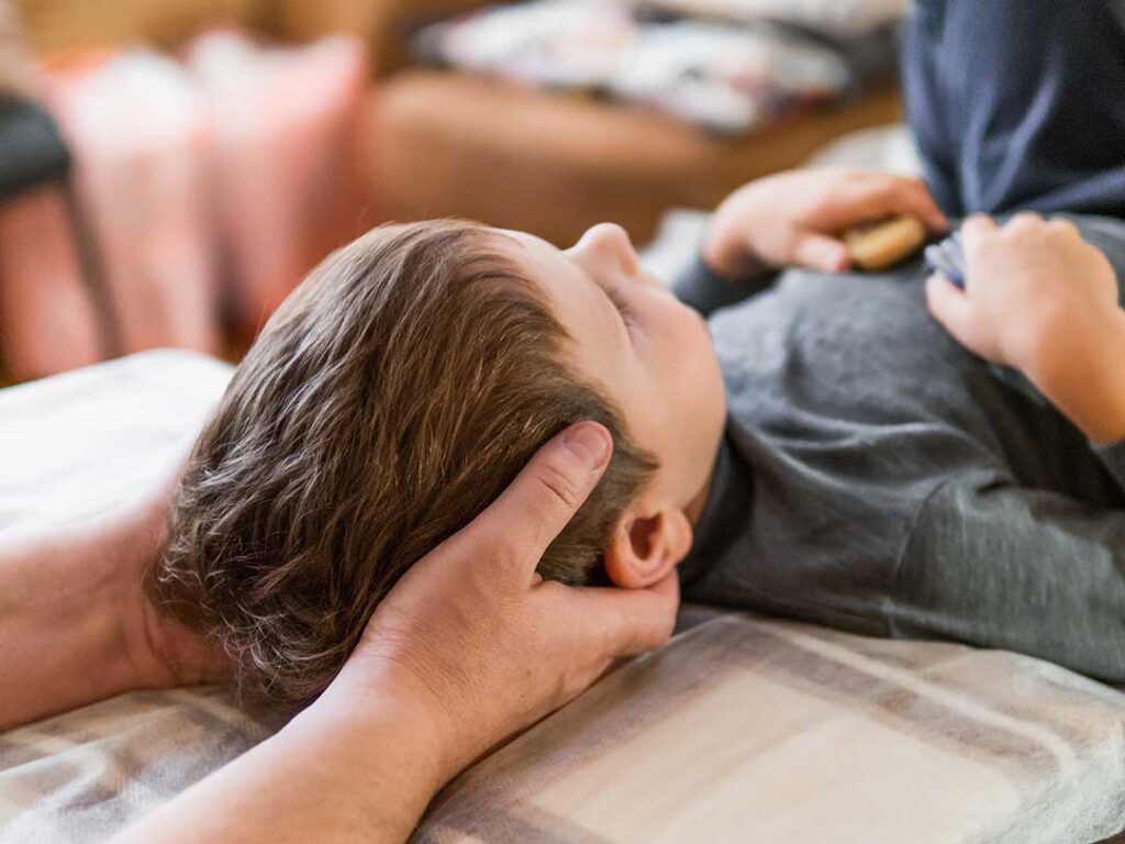 A chiropractor gently examines a patient's neck in a bright, comfortable clinic setting.
