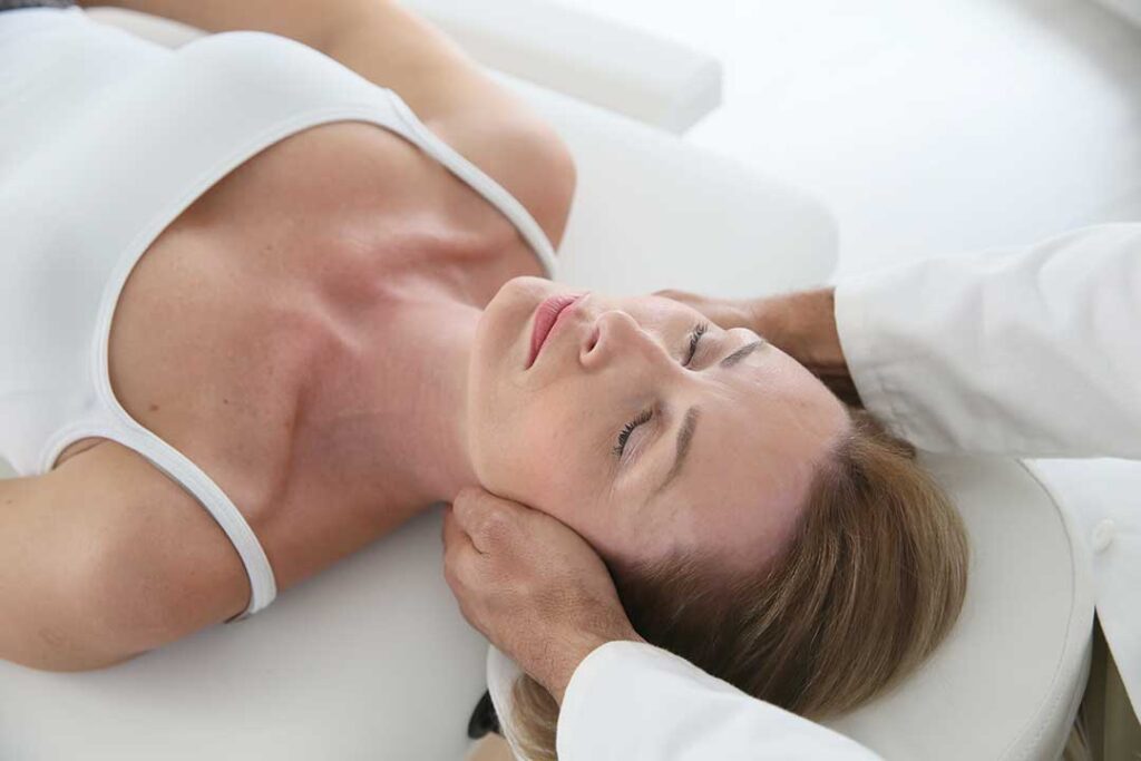 Patient discusses back pain with a chiropractor during a first examination in a calm clinical room.